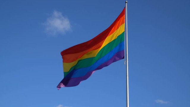 LGBT Gender Equality Symbol Rainbow Flag Waiving in Blue Sky -Wide Shot-