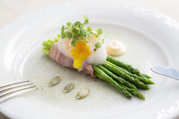Poached egg over green asparagus on a plate