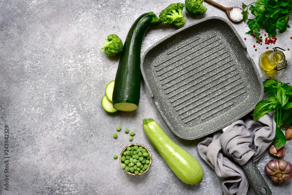 Wall mural Culinary background with empty cooking pan, green vegetables, herb and spices.Top view with copy space.