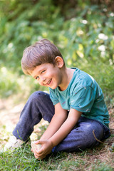 boy sitting on grass, enjoying hot summer day in nature, smiley happy face expression