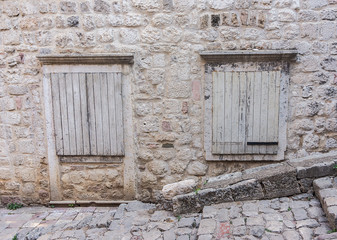Fototapeta na wymiar Windows closed with wooden shutters in the stone wall