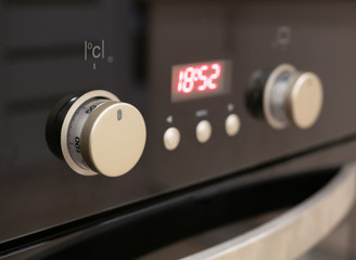 closeup of control dials and buttons of modern kitchen oven. selective focus on closest knob with blurred digital display