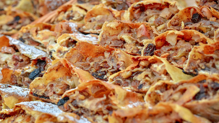Many sweet apple strudels with raisins, nuts and honey. Selective focus.