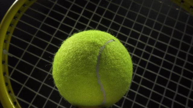 Sports and games. Close up of a  tennis ball rotating and moving forwards and backwards in front of a tennis racket.