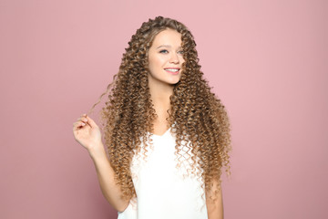 Portrait of beautiful young woman with shiny wavy hair on color background