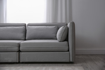 Simple living room interior with comfortable sofa near window