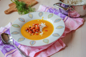 Healthy vegan pumpkin cream soup with rice, apples, roasted carrots and fresh herbs