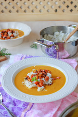 Healthy vegan pumpkin cream soup with rice, apples, roasted carrots and fresh herbs
