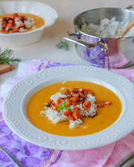 Healthy vegan pumpkin cream soup with rice, apples, roasted carrots and fresh herbs