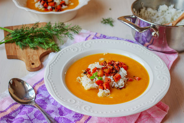 Healthy vegan pumpkin cream soup with rice, apples, roasted carrots and fresh herbs