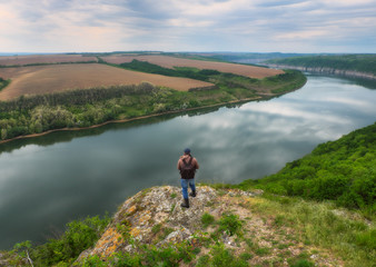 tourist on a cliff above the canyon. person on a cliff above the picturesque river. spring dawn
