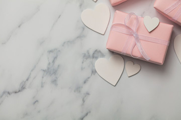 Pink valentine gift with white hearts on a marble background