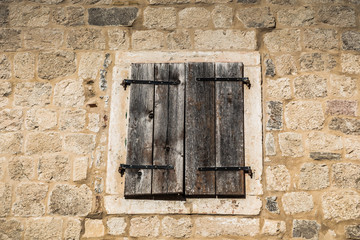 Closed old wooden window on stone wall - 243951333