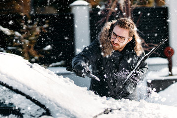 Heavy snowfall. Details of man cleaning car from snow