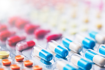 Heap of medical pills in white, blue and other colors. Pills in plastic package. Concept of healthcare and medicine.