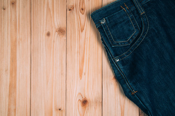 Frayed jeans or blue jeans denim collection on rough wooden table background with copy space, old fashion concept.