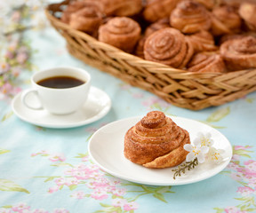 Cinnamon buns with tea and spring flowes on a table