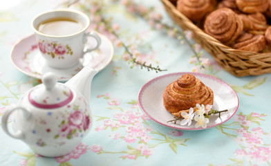 Cinnamon buns with tea and spring flowes on a table