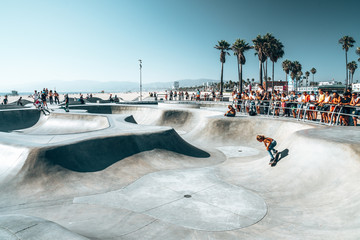 June 10, 2018. Los Angeles, USA. Venice beach skate park by the ocean. People skating at the skatepark showing different tricks.  - obrazy, fototapety, plakaty