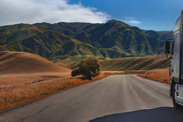 Long vehicle driving along an asphalt road among the mountains. Road in mountains. 