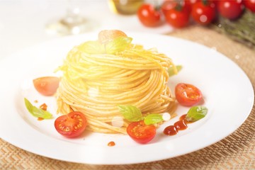 Spaghetti pasta with cherry tomatoes and basil leaves on white