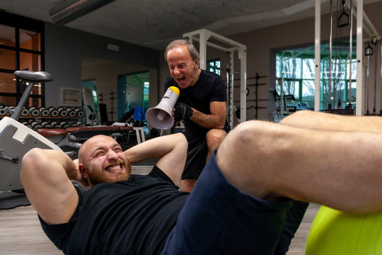 senior trainer screaming with a megaphone at the young athlete