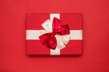 Real box with white and red bow and ribbon top view on Valentine's day isolated on red background. Flat lay. Copy space