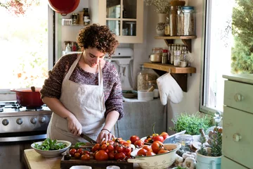 Crédence de cuisine en verre imprimé Cuisinier Woman slicing tomatoes for pasta sauce