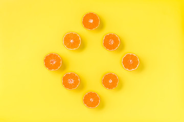 Fruit pattern of fresh mandarin slices on yellow background. Flat lay, top view. Pop art design, creative summer concept. Half of citrus in minimal style. Tangerine.