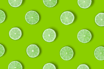 Fruit pattern of lime slices on green background. Flat lay, top view.