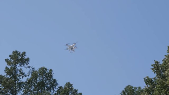 Flying helicopter dron on a background of white clouds.