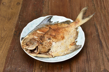 Fried white pomfret on wooden table