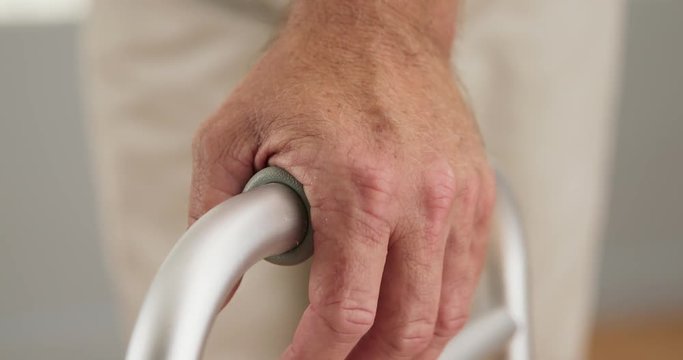 Close up on hands of senior man grasping the handles of a walker