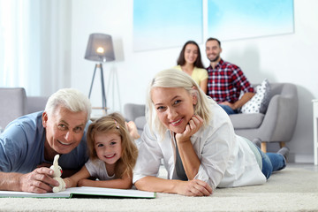 Fototapeta premium Mature couple spending time with their granddaughter at home. Happy family