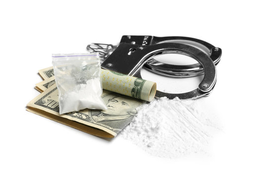 Cocaine, money bills and handcuffs on white background