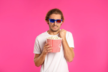 Fototapeta premium Emotional man with 3D glasses and popcorn during cinema show on color background