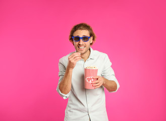 Naklejka premium Emotional man with 3D glasses and popcorn during cinema show on color background