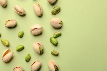 Fototapeten Organic pistachio nuts on color background, flat lay. Space for text © New Africa