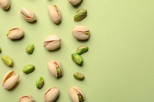 Fototapeta Organic pistachio nuts on color background, flat lay. Space for text