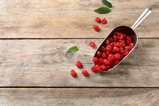 Scoop of sweet cherries on wooden background, top view with space for text. Dried fruit as healthy snack