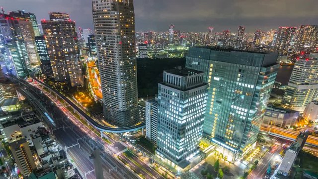 Timelapse Overview of City Transit below Tokyo Skyline at Night -Tilt Down-