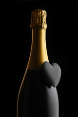 Closeup of a bottle of Champagne with a black heart against a black background