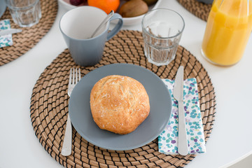 Plate with fresh crusty bread and glass of juice on grey plate