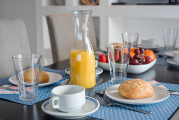 Plate with fresh crusty bread and glass of juice on white plate