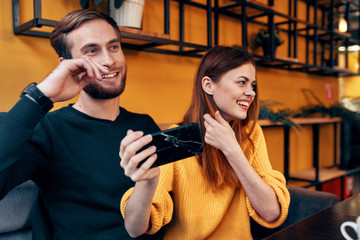 Naklejka premium young couple laughing in the hands of a smartphone cafe