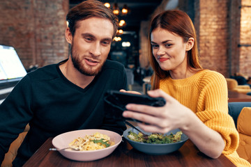 young couple laughs look in smartphone cafe