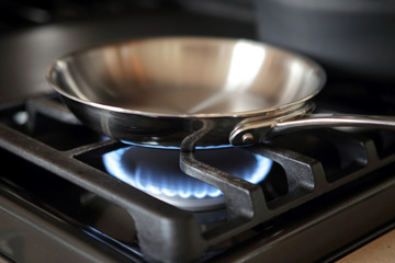 Stainless steel pan heating up on gas range stove.