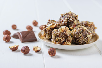 Scattered on a white table hazelnuts and sweets of grated nuts and dried fruits on a wooden white table.