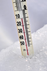 Mercury thermometer in the snow showing negative temperature Celsius. Close up