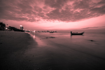 The background of the sea and the evening twilight by the beach, is a natural beauty each day, with fishing boats docked and there is a blur of ocean waves